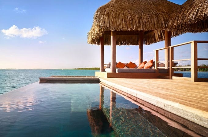 infinity pool with poolside lounging area with a hut overlooking the beach in Four Seasons Bora Bora