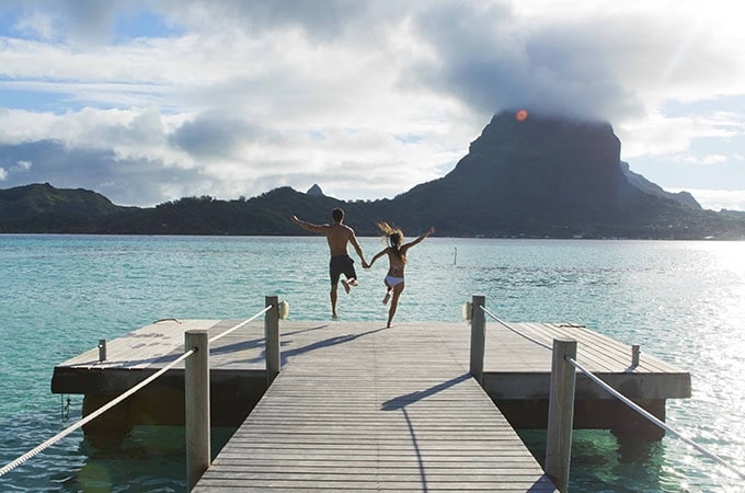 Couple in Tahiti jumping in water