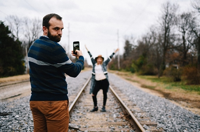 Man taking photo of woman on train track