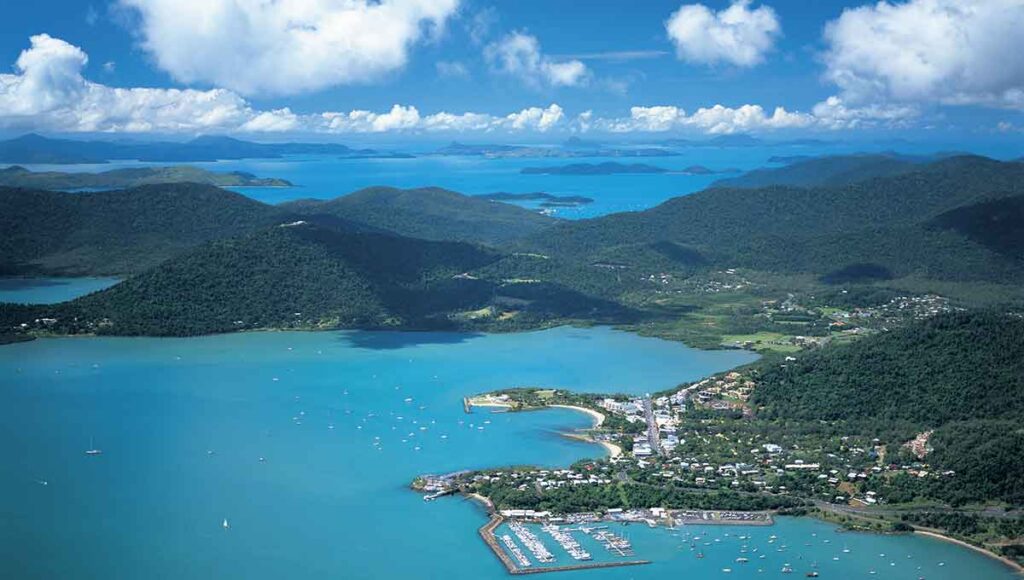 An aerial view of the Airlie Beach with lush greeneries on mountain ranges - ultimate australian honeymoon