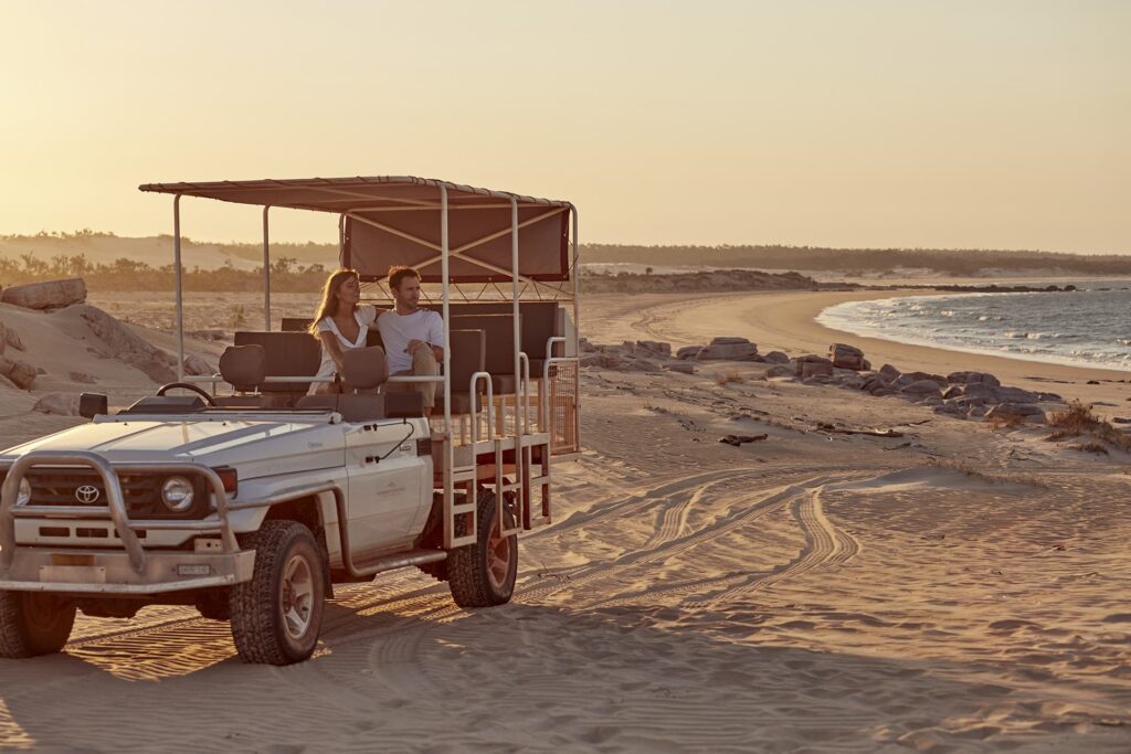 A couple sitting on an off-road vehicle on the beach during sunset