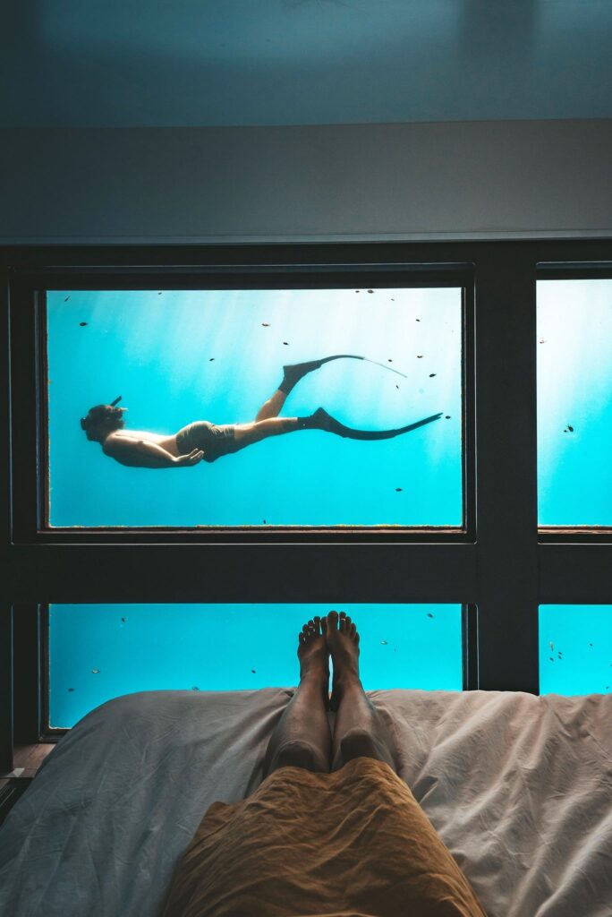 a man laying on the bed in Reefsleep Whitsundays underwater room with a man swimming outside