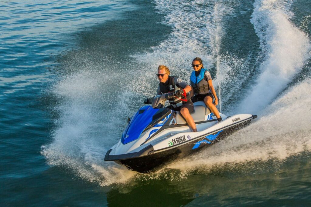 A couple riding a jet ski on a beach with Gold Coast Watersports