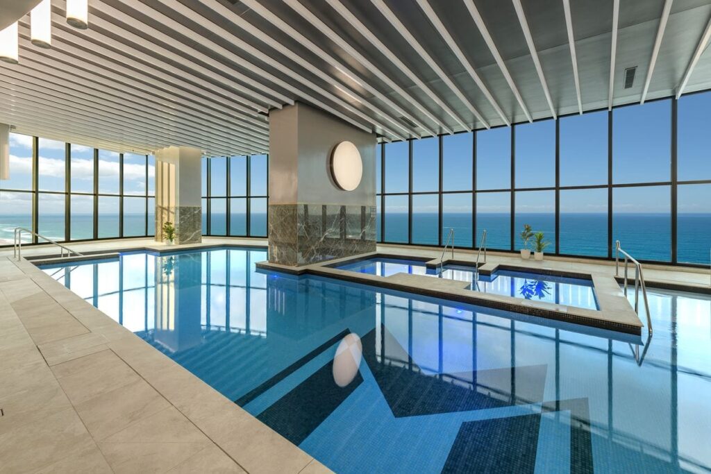 Indoor pool at Meriton Suites in The Gold Coast during daytime with glass walls and views of the beach
