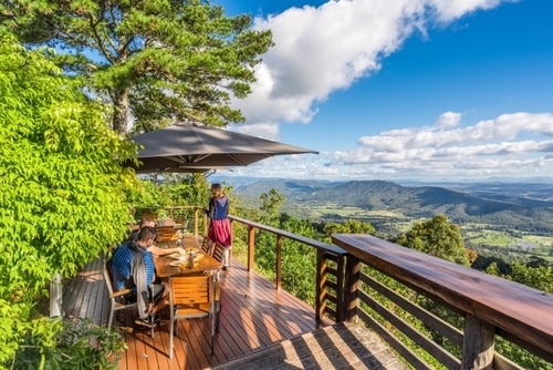 Cottage or treehouse style restaurant with a few people eating at The Polish Place Tamborine Mountain with scenic aerial views of the surrounding green fields and mountains