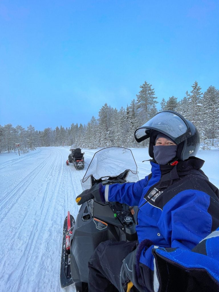 Snowmobiling-in-finland-snow-snowmobile-snowy-mountains-with-trees-in-the-background