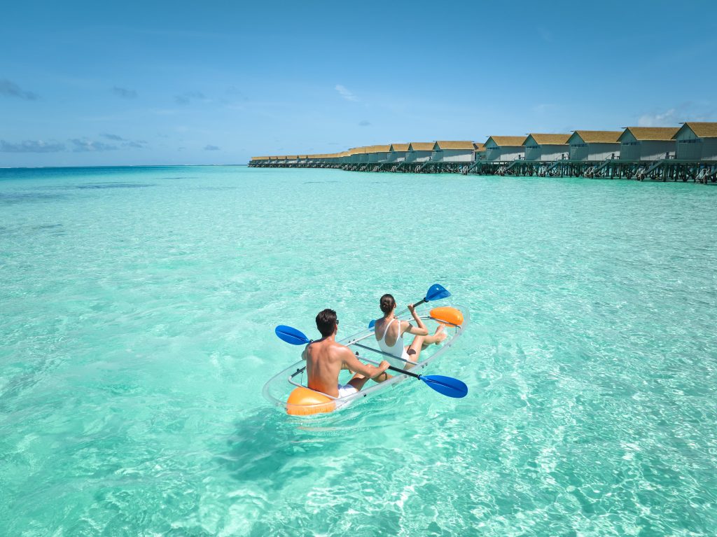 Centara-ras-fushi-resort-and-spa-maldives-drone-shot-of-a-couple-kayaking-on-a-clear-beach