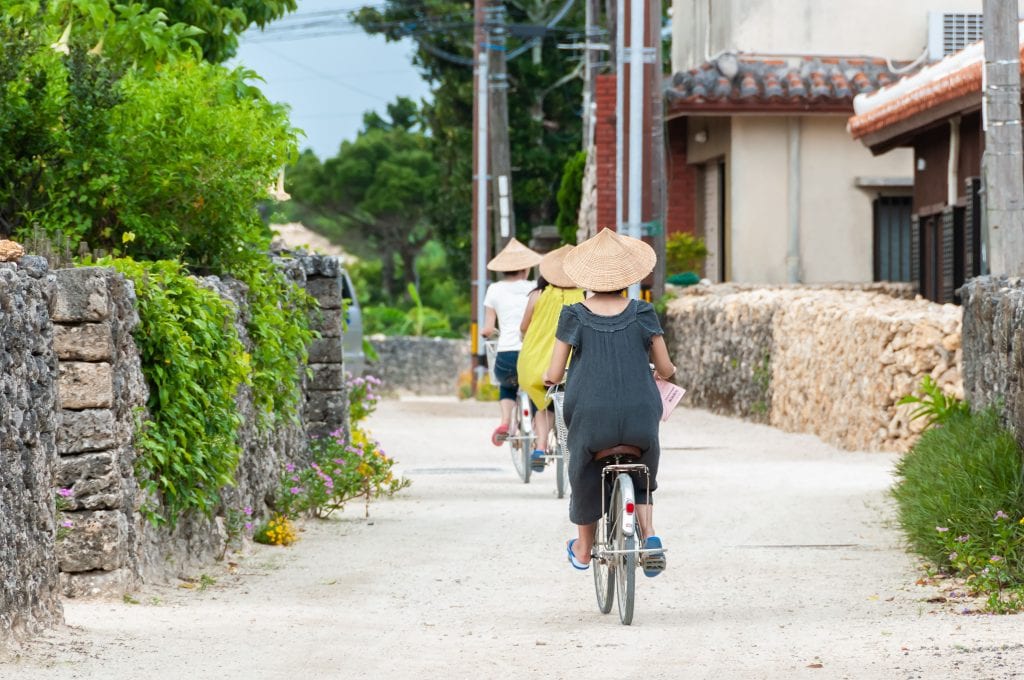 Three people riding bicycle h the traditional village of Taketomi Okinawa