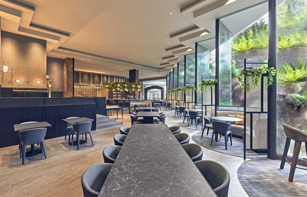 An empty dining area with chairs, tables, counters, and floor to ceiling glass windows or doors at the Orchard Diner in Vibe Hotel Singapore
