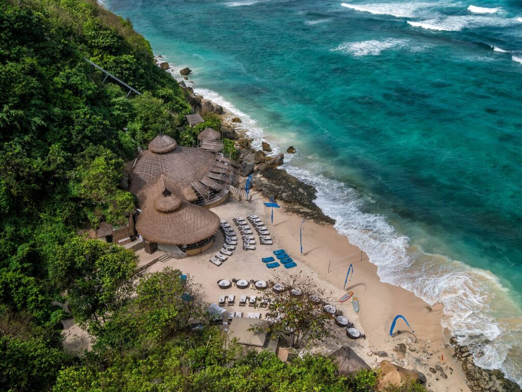 Bird's eye view or drone shot of Karma Beach Club in Bali with white sand beach and beachside lounge chairs
