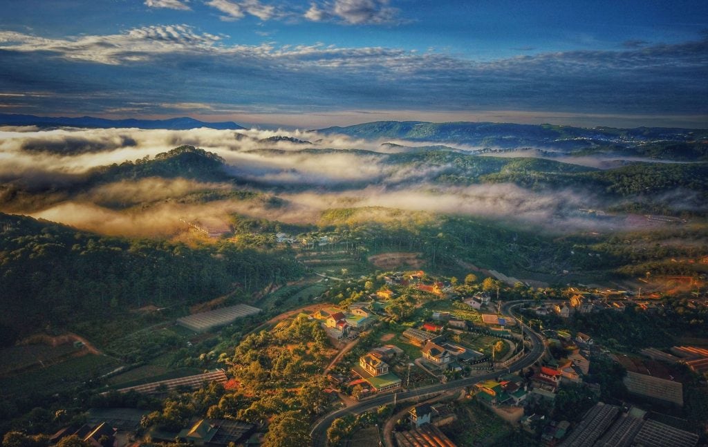 Overhead or drone shot of a foggy mountain with a small town in Da Lat Vietnam