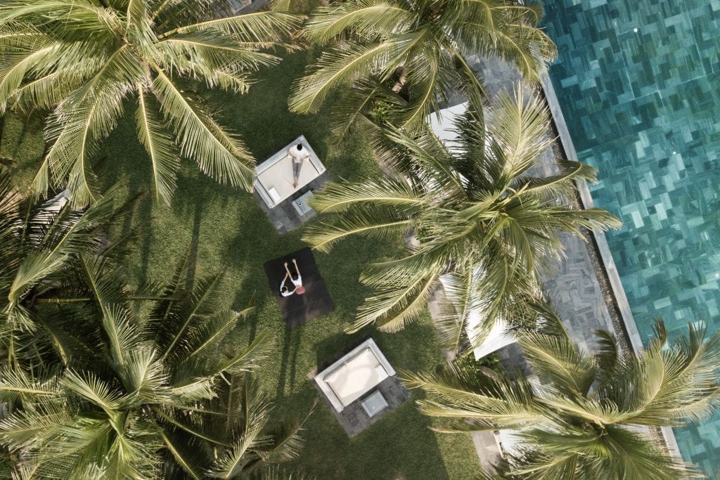 Drone or overhead shot of TIA Wellness Resort Beach Living with palm trees and a swimming pool