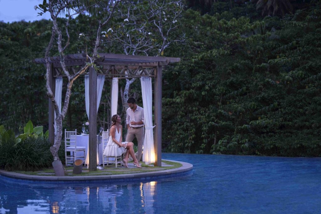 The-Westin-Resort-Spa-Ubud-couple-by-the-infinity-edge-swimming-pool-at-nighttime