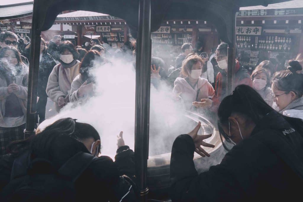 Asakusa - Japan - people worshipping and using incense on a temple